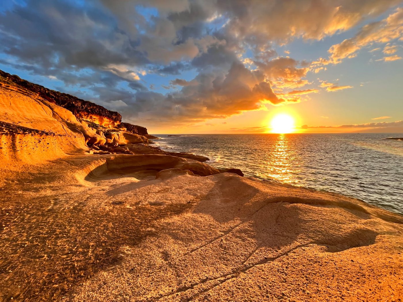 Solnedgang over kysten med dramatiske skyer