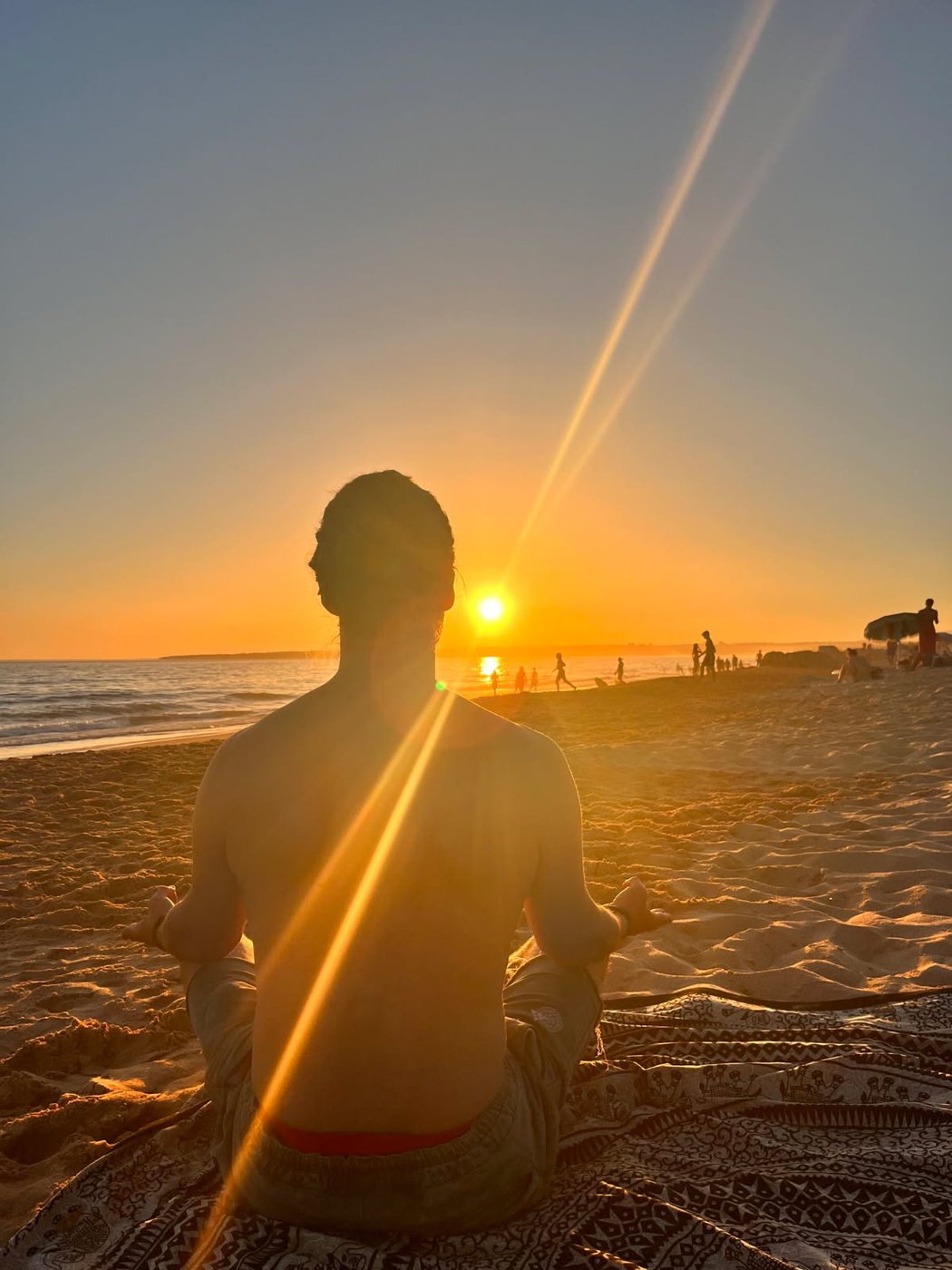 Silhuett i meditasjon ved solnedgang på stranden